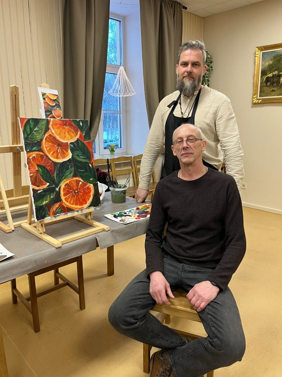 Mākslas pietura pasniedzējs un dalībnieks pie pabeigtas gleznas