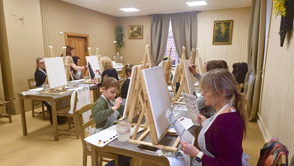 Spāres muižas telpās dalībnieki glezno pie galdiem un molbertiem uz audekliem